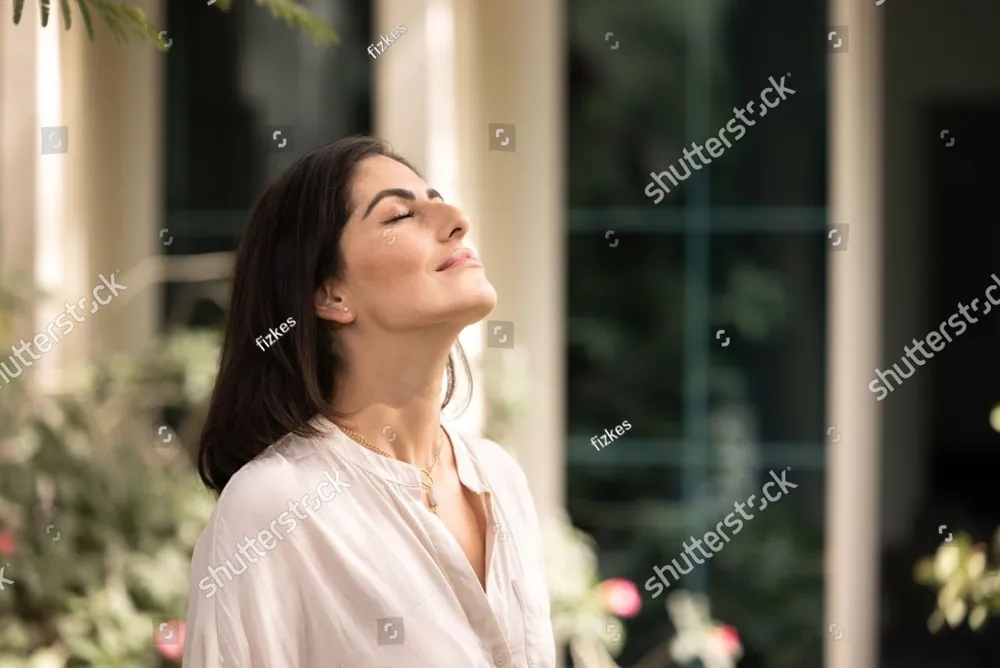 A woman with her eyes closed, her face lifted to the sunlight