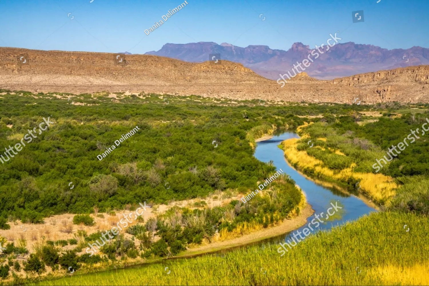 A green river winding through a wide Texas valley toward distant mountains