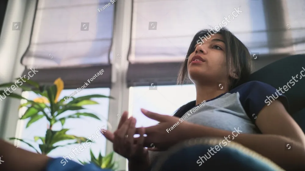 A teenage girl talking and gesturing in a sunlit room